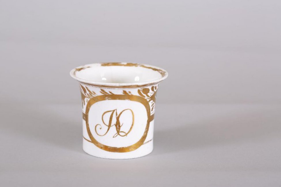 Чашка цилиндрическая, верх раструбом, ручка петлевидная; роспись золотом: монограмма "АО" в золоченом резерве; кругом орнамент из двух ромбов и стилизованных лиственных мотивов